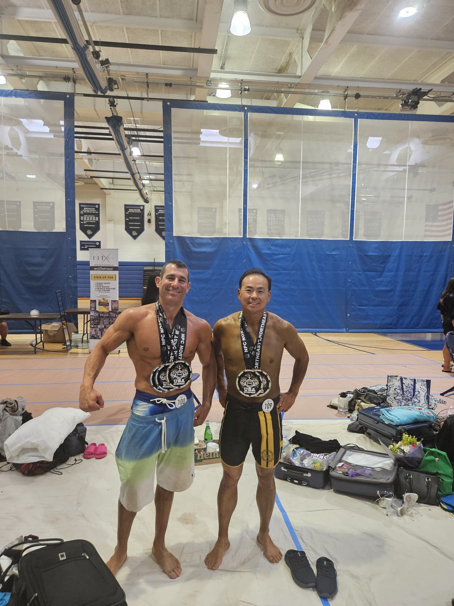 Two physique competitors wearing their medals in a gym