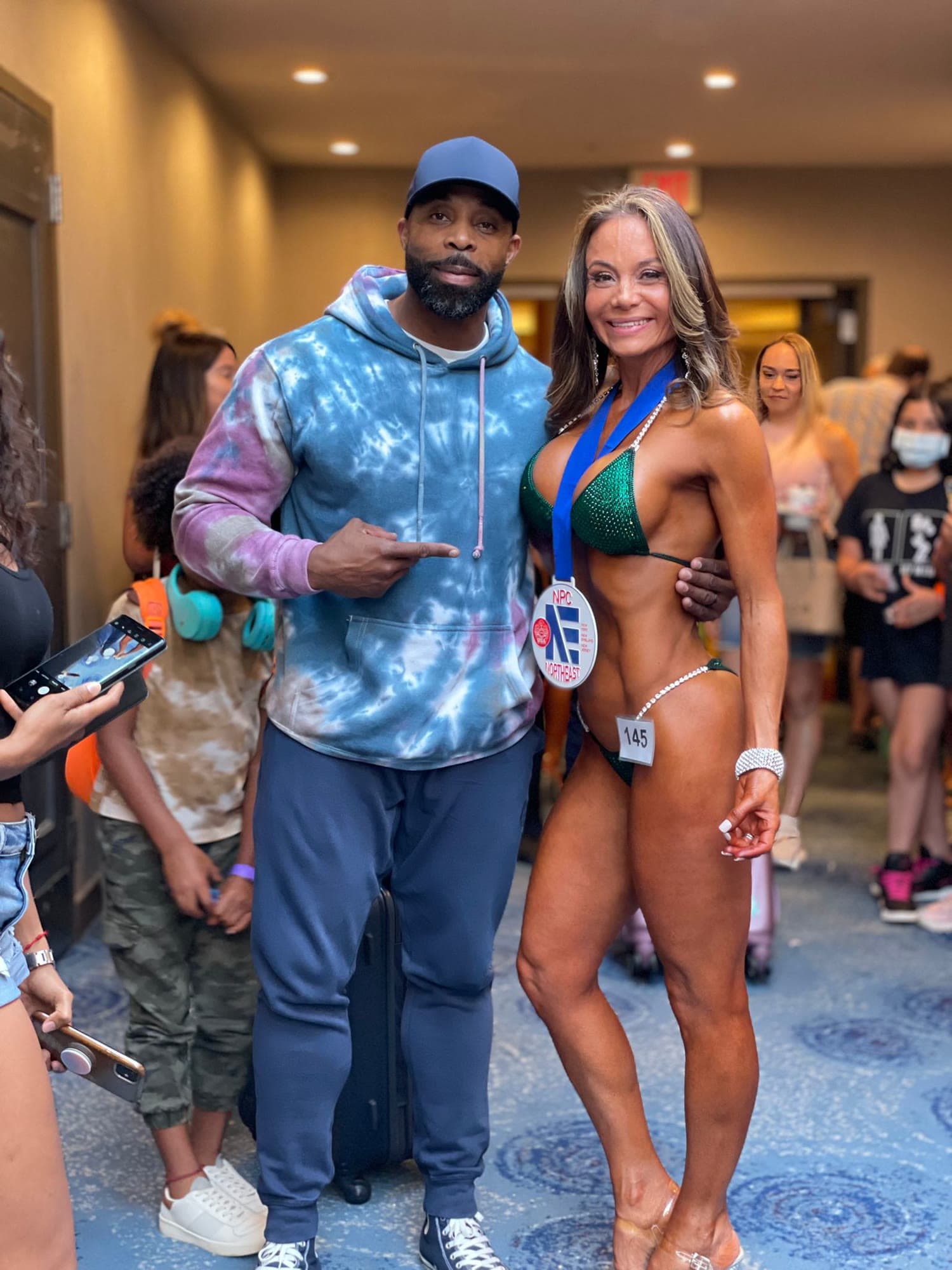 Daine Chang backstage with a bikini competitor wearing her medal