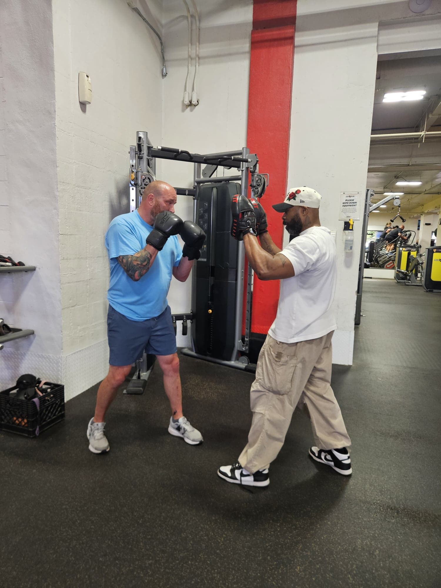 Daine Chang holding pads for a client in boxing gloves