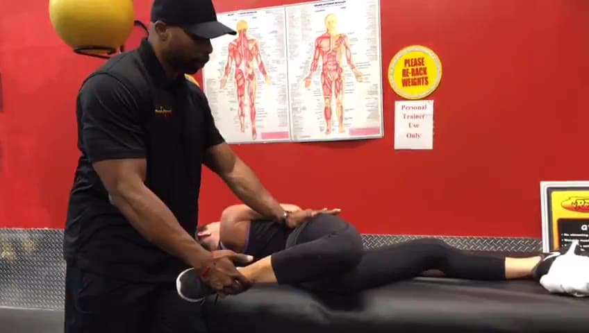 Daine Chang opening a client's leg out to the side on the table