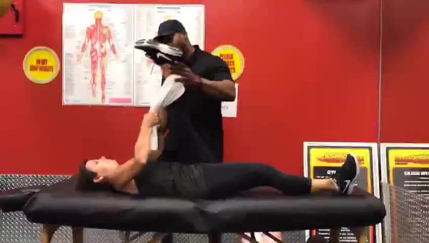 Daine Chang taking a client's bent knee across the body on the table