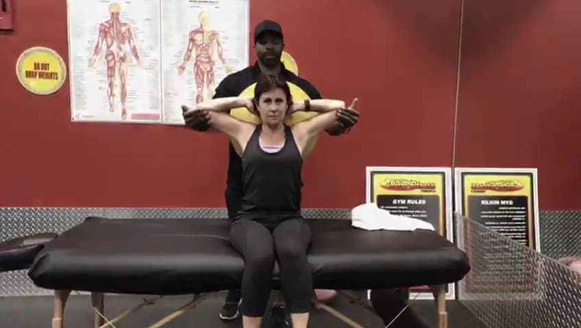 Daine Chang opening a seated client's chest, hands behind the head