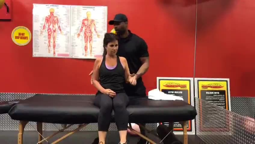 Daine Chang pulling a seated client's arm across the chest